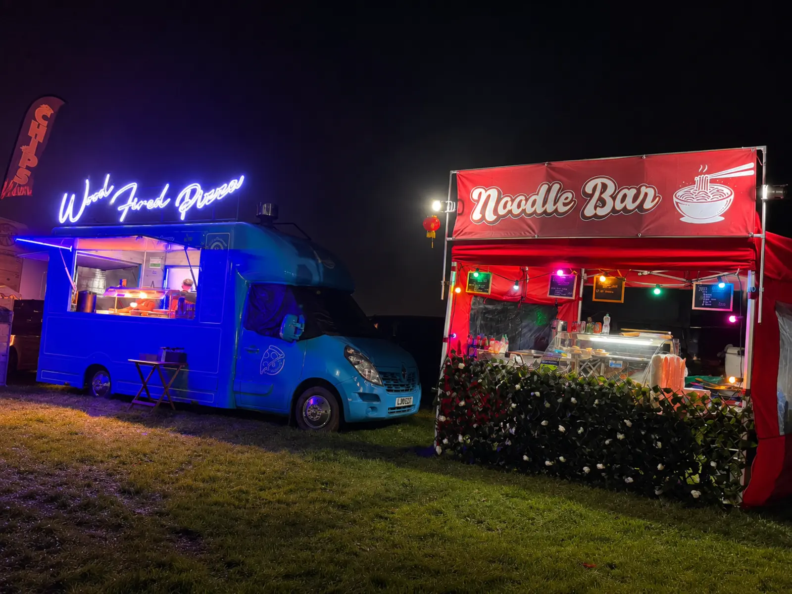 A wood-fired pizza truck and noodle bar trading together at a nighttime event