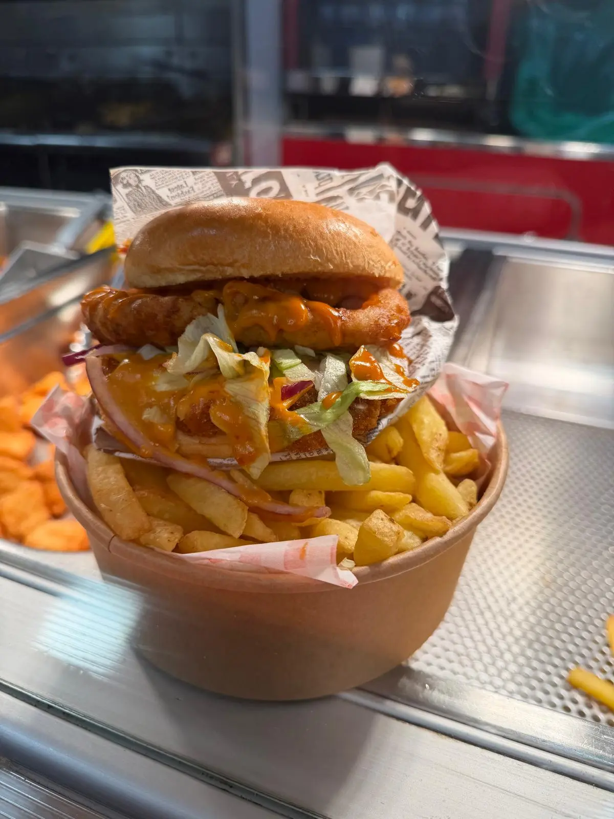 A freshly prepared street-food burger served with chips
